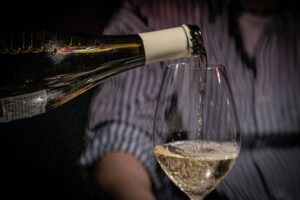 Weißwein wird aus Flasche in Glas eingegossen